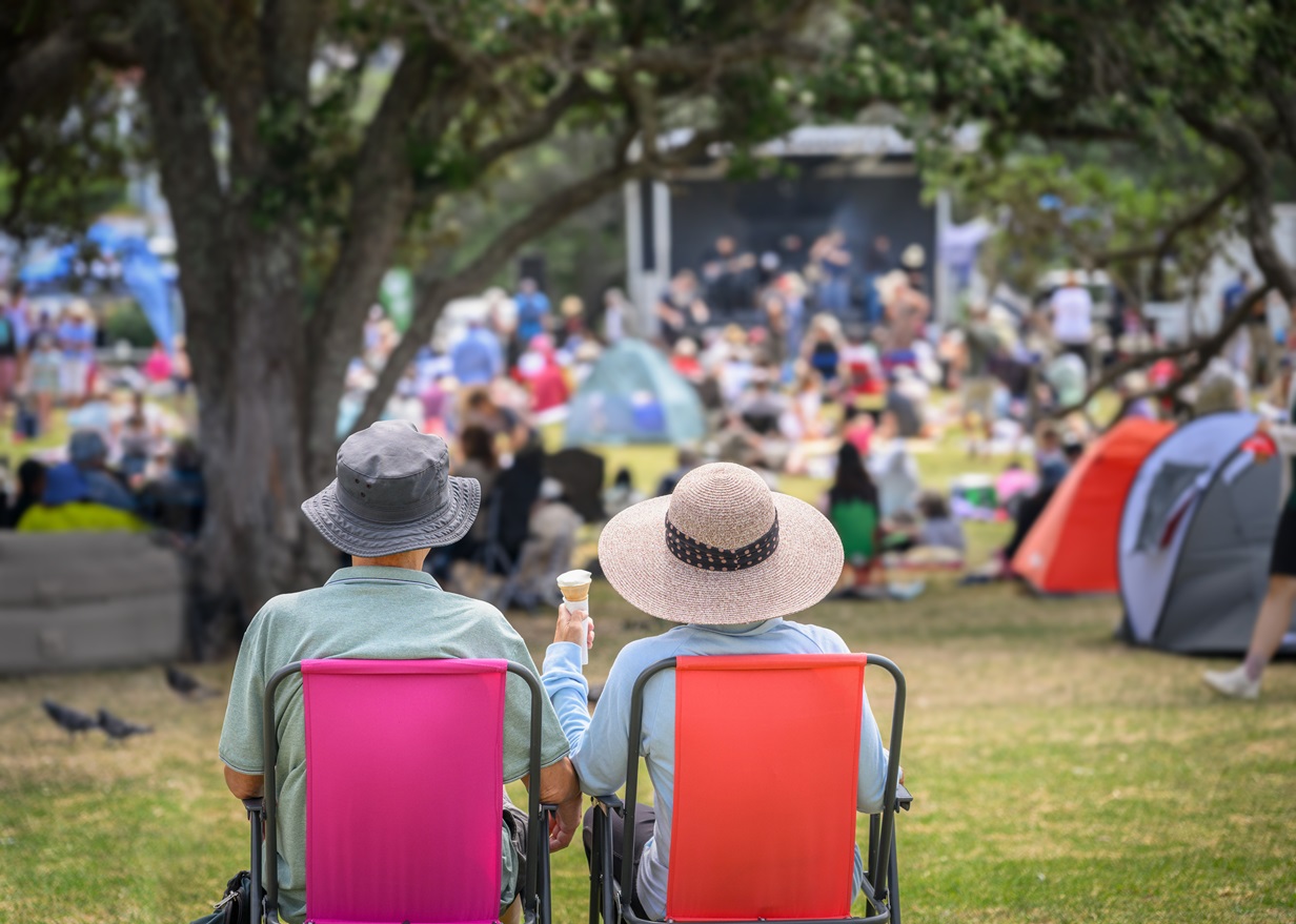A back view of a couple seated in lawn chairs at an outdoor concert.