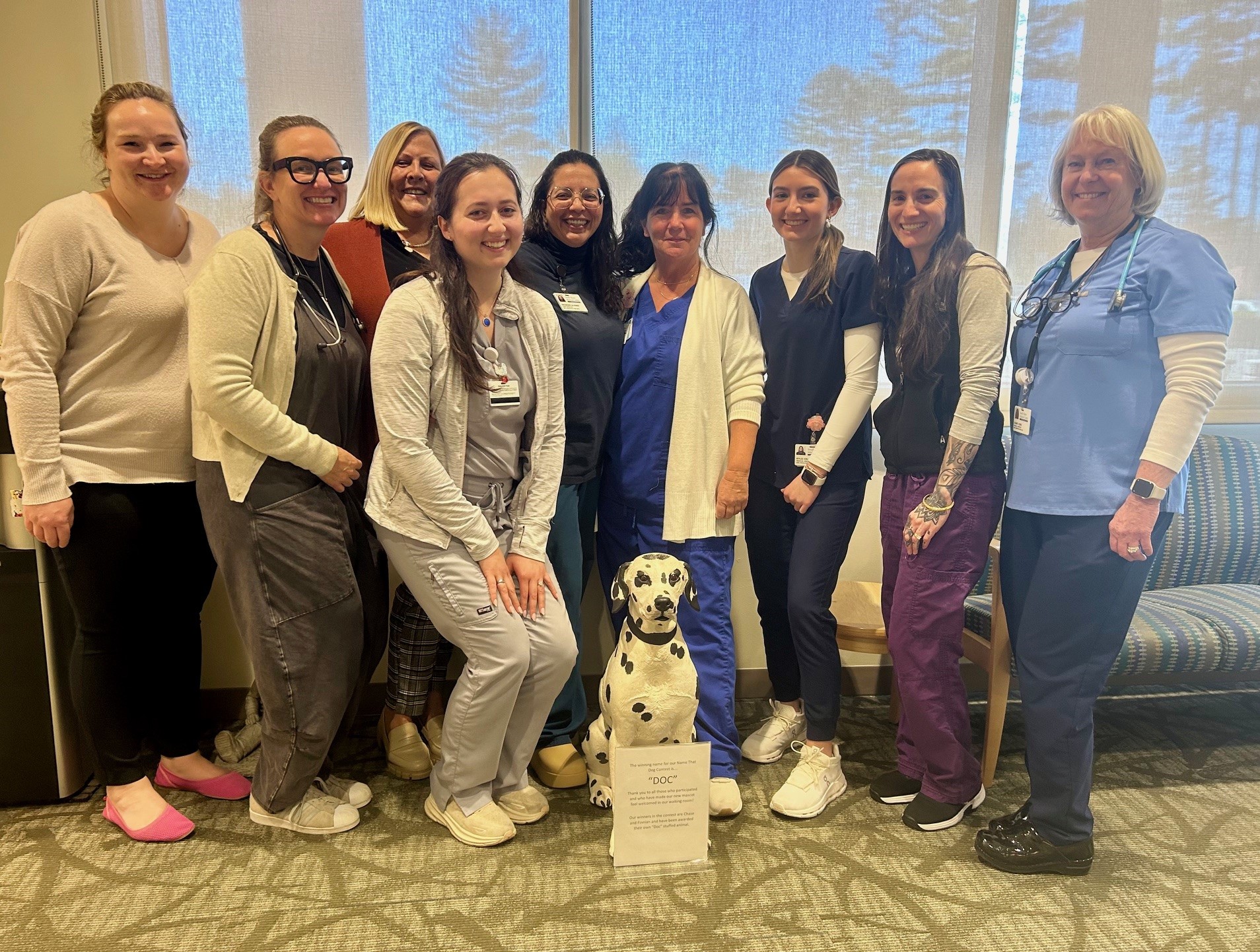 The staff stand around the pediatric department Dalmatian dog mascot "Doc"
