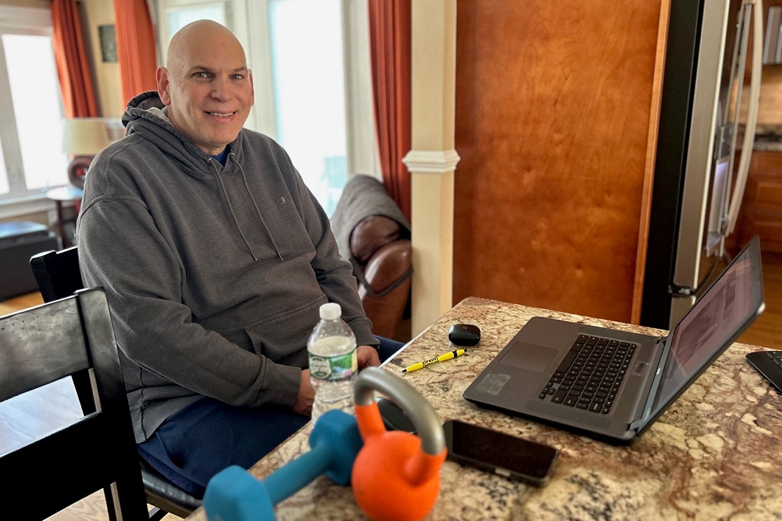 A man sitting in front of a laptop smiling