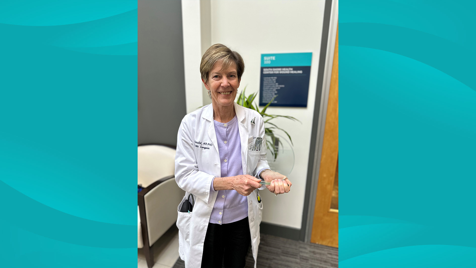 South Shore Health's Lisa Gould, MD, PhD poses for a photo holding a clear glass award.