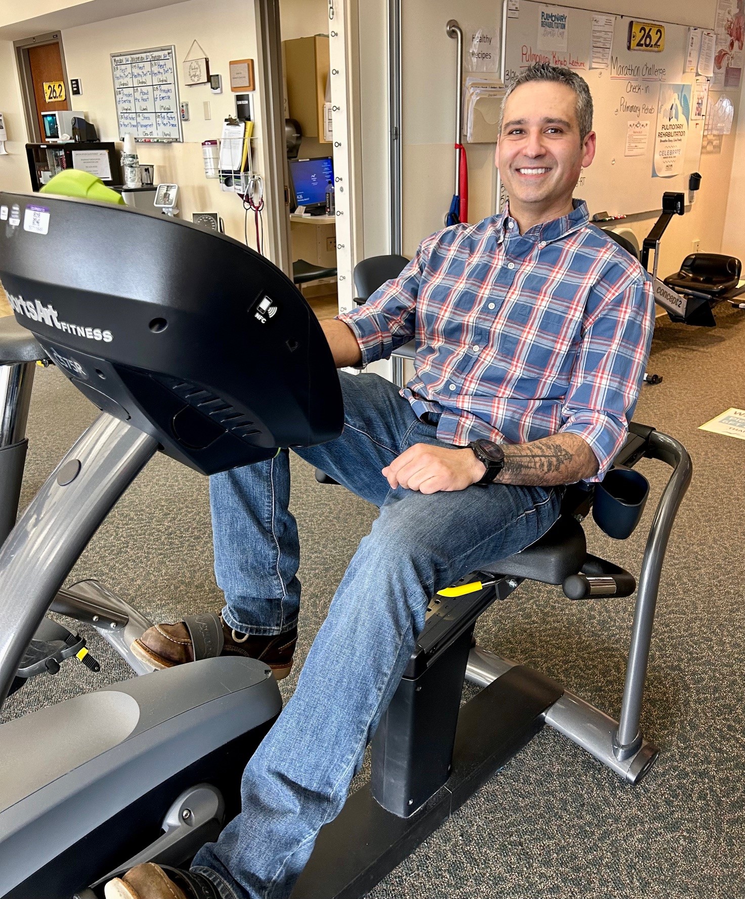 A male patient sitting on a hand bike machine in cardiac rehab
