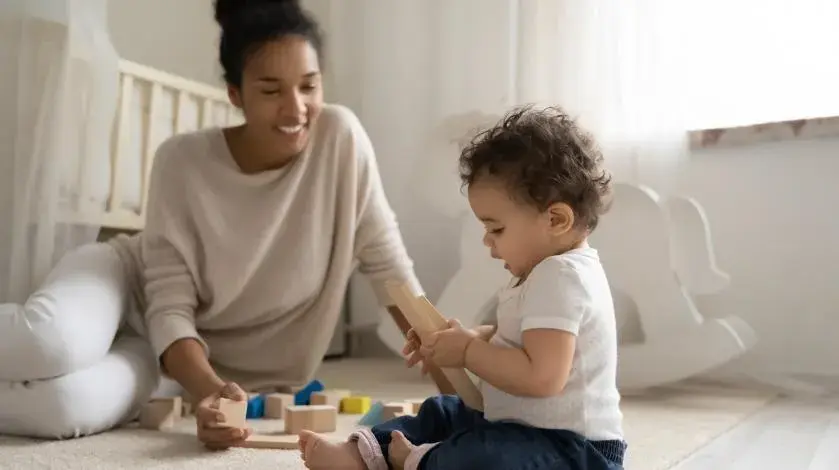 Baby sitting with his mom and playing with blocks