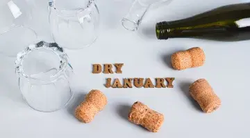 Dry January graphic with an empty wine bottle, corks and overturned glasses
