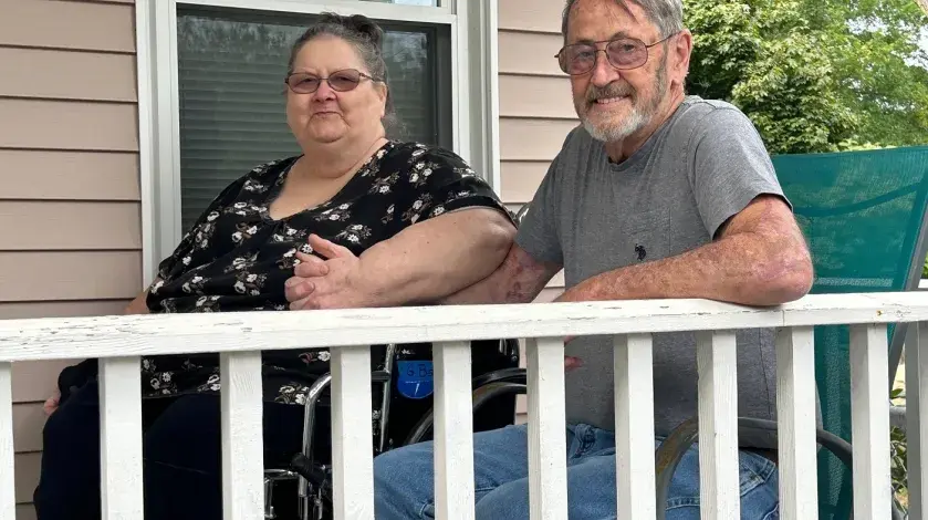 Georgeanne and Bill Barnes holding hands sitting on their porch