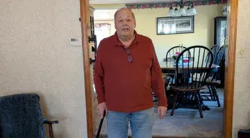 John of Rockland poses for a photo in his living room after an at-home outpatient rehab appointment.