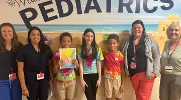 Kids from Kids Who Care pose for a photo with members of South Shore Hospital's Pediatrics Unit