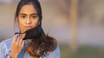A young woman taking off her face mask 