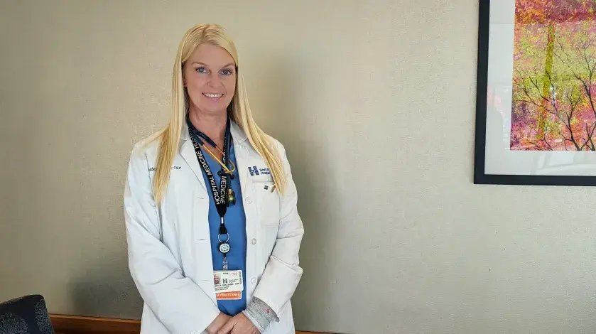 A photo of Rebecca Graziano, CNP of South Shore Hospital, wearing a white lab coat and scrubs.