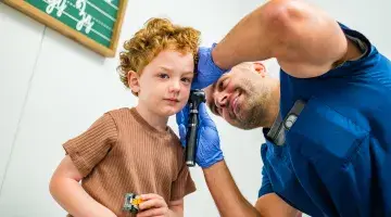 A young boy has his ears checked at an urgent care center
