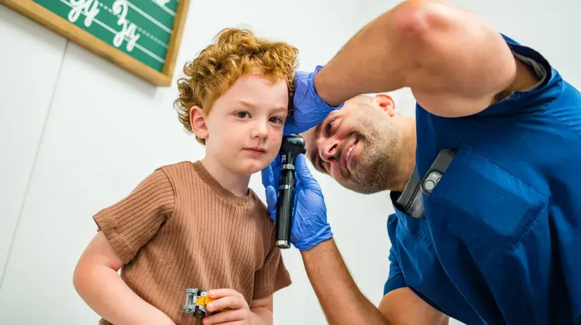A young boy has his ears checked at an urgent care center