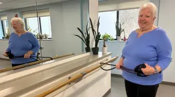 Sue Cullinan poses for a photo by the mirror in the senior strength training class