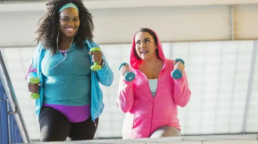 Two women walking together with weights