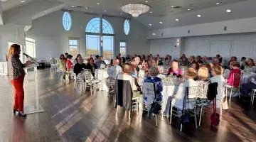 A shot of a ballroom at Granite Links in Quincy as Amy Parker speaks at the podium at South Shore Health's Volunteer Appreciation Dinner