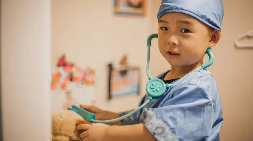 Young Asian boy dressed as a doctor uses stethoscope on a stuffed toy
